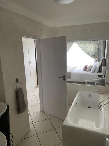 un baño con lavabo y una cama en una ventana en No 21 Marina Palms, en Hibberdene