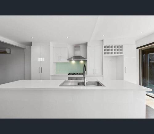 - une cuisine blanche avec évier et cuisinière dans l'établissement Entire contemporary home in Ascot Vale, à Melbourne