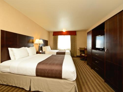 a hotel room with two beds and a flat screen tv at Yellowstone West Gate Hotel in West Yellowstone