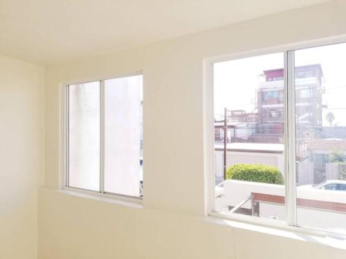 two windows in a white room with a view of a building at Tu Casa de Familia in Tijuana