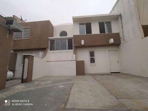 uma grande casa branca com uma garagem e uma entrada em Tu Casa de Familia em Tijuana