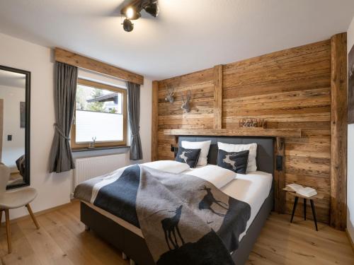 a bedroom with a large bed and a wooden wall at Alpine Lodge Brixen in Brixen im Thale