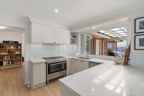 a kitchen with white cabinets and a stove top oven at Serene Pet Friendly with Swimming Pool in Culburra Beach