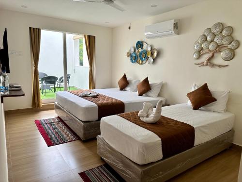 a bedroom with two beds and a balcony at Hotel Ramakrishna in Mahabalipuram