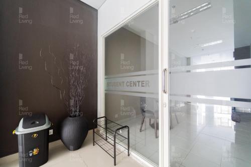 a room with a glass door with a vase and a chair at RedLiving Apartemen Barsa City by Ciputra - WM Property in Yogyakarta