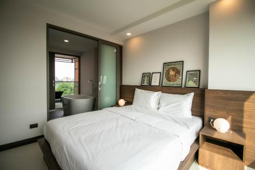 a bedroom with a large white bed and a bathroom at ECOndo Bangsaray in Bang Sare