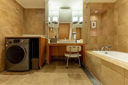 a bathroom with a washing machine next to a bath tub at Hotel Metropolitan Premier Taipei in Taipei