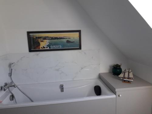 een badkamer met een wit bad en een foto aan de muur bij Les Tilleuls in Plestin-les-Grèves