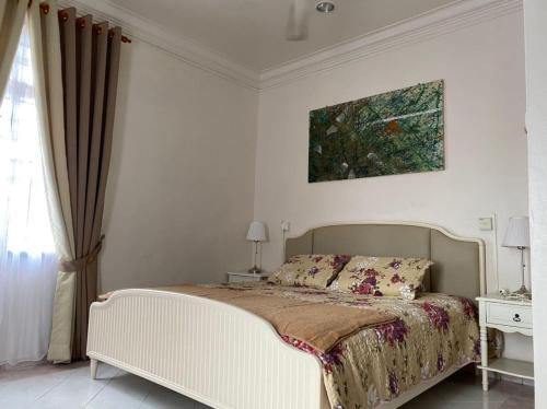 a bedroom with a bed and a painting on the wall at Dahan Homestay in Kota Bharu