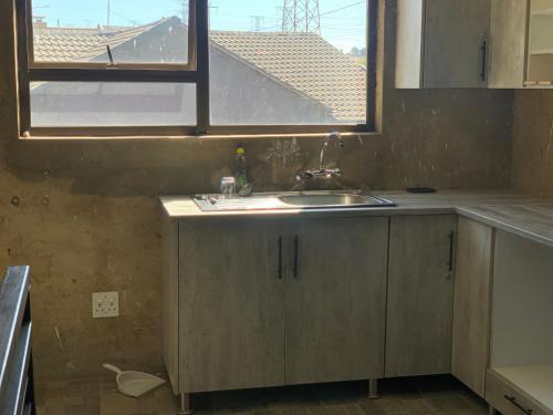 cocina con fregadero y ventana en Orlando Manor, en Soweto