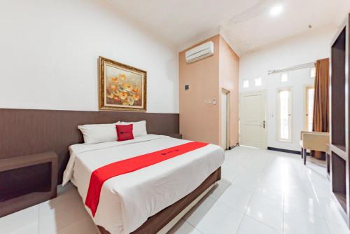 a bedroom with a large bed with a red blanket at RedDoorz near Kejaksan Station Cirebon in Cirebon