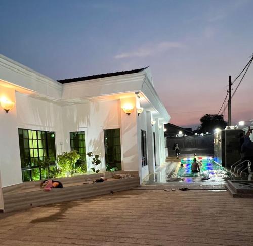 Biały dom z ludźmi leżącymi na ziemi w obiekcie Aainaa Villa Homestay w mieście Pasir Mas