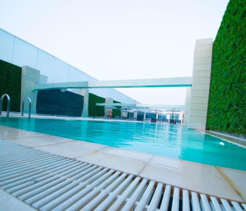 a swimming pool with a bench in front of a building at Sarwat Park Hotel Riyadh - Diplomatic Quarter in Riyadh