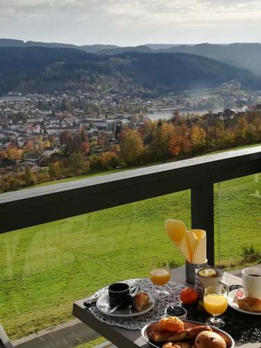 - une table avec de la nourriture et des boissons sur un balcon avec vue dans l'établissement Duplex Estelle - 2 couples ou famille, à Gérardmer