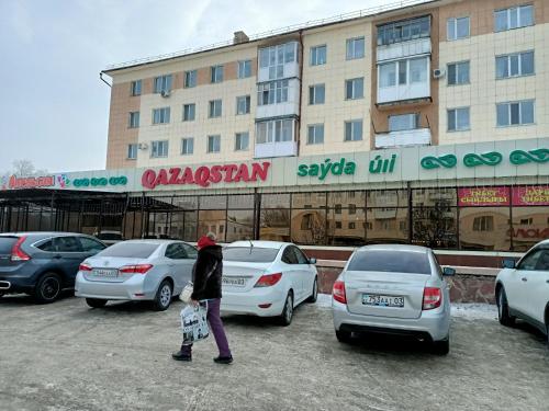 a person standing in a parking lot next to cars at 1 комн. Апартаменты на Абая 122 in Kokshetau