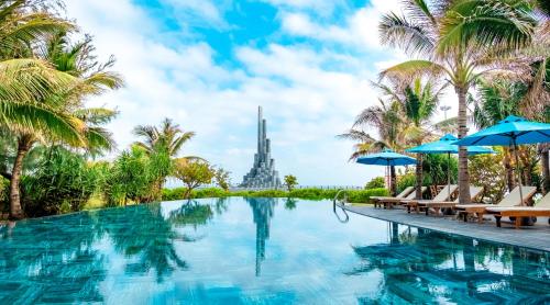 einen Pool mit Palmen und Blick auf den Eiffelturm in der Unterkunft Stelia Beach Resort in Tuy Hoa