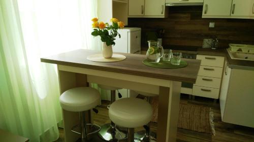 a kitchen with a table with a vase of flowers on it at Aqualiget-Apartmanház E-Car plug-in point Szeged in Szeged