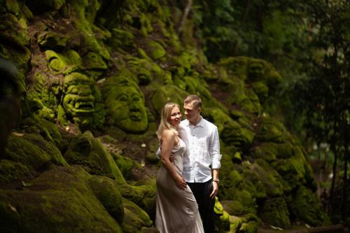 a bride and groom standing in front of a rock wall at Ayung Resort Ubud in Payangan