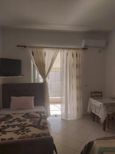a bedroom with a bed and a window and a table at Mona`s apartments 1 in Sarandë