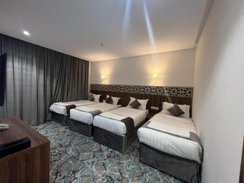 فندق بياك أوتيل الروضة في مكة المكرمة: غرفة في فندق بثلاث اسرة في غرفة