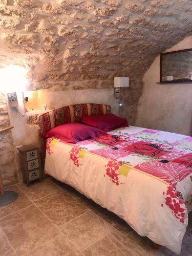 une chambre avec un lit dans un mur de pierre dans l'établissement Le Mas Draiou Ecogites - 2 gites et une chbre familliale combinables 14 pers, à Saint-Restitut