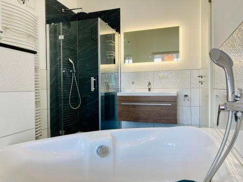 a bathroom with a tub and a shower and a sink at Villa Anna App. 7 Seeblick in Heringsdorf