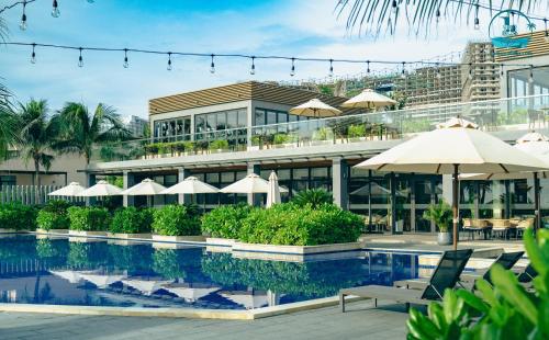 ein Resortpool mit Sonnenschirmen und ein Gebäude in der Unterkunft Lumina Villas Cam Ranh, Bai Dai beach luxury resort villas in Cam Ranh