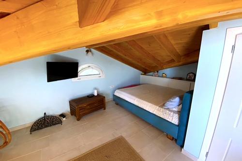 a small bedroom with a bed and a tv at Beachfront Loft Apartment - Agios Gordios, Corfu in Agios Gordios