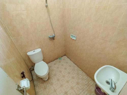 a small bathroom with a toilet and a sink at Oka Homestay Mitra RedDoorz in Mataram