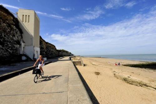 a woman riding a bike on the beach at Wolverdene - Entire ground floor flat with garden in Margate