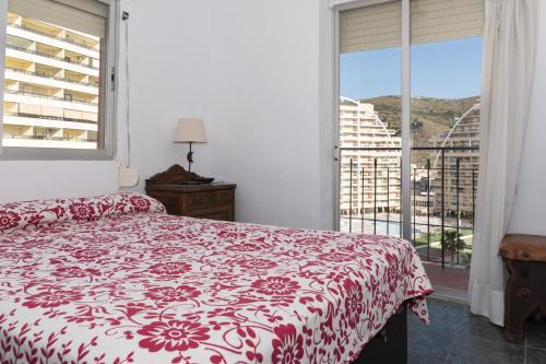 sypialnia z czerwono-białym łóżkiem i oknem w obiekcie EL RACO- C, 8-16 w mieście Cullera