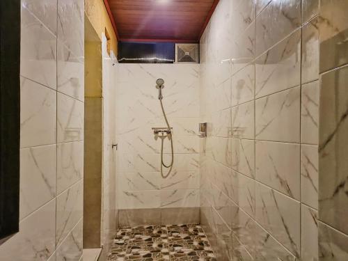 ein Bad mit einer Dusche und weißen Marmorfliesen in der Unterkunft Sanga Suites in Ubud