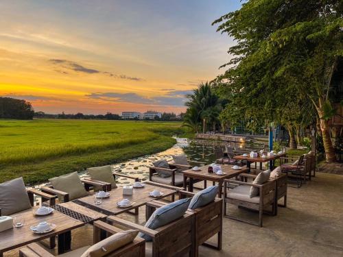 a restaurant with tables and chairs next to a river at KEPT Cabana เคปท์ คาบานา in Lampang