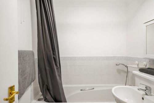 La salle de bains blanche est pourvue d'un lavabo et d'une baignoire. dans l'établissement Cozy Luton Town Centre Retreat, à Luton