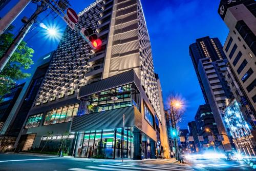 a tall building on a city street at night at The Royal Park Canvas - Osaka Kitahama in Osaka
