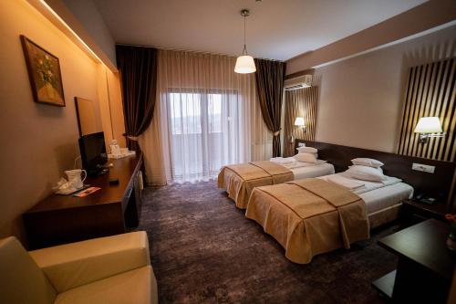 a hotel room with two beds and a couch at Hotel Secret Garden in Baia-Sprie