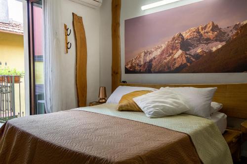 1 dormitorio con 1 cama y una gran pintura en la pared en Le Coccinelle Home, en Mandello del Lario