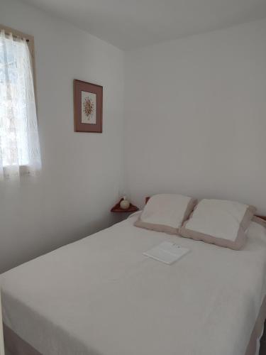 ein weißes Bett in einem weißen Zimmer mit Fenster in der Unterkunft Appartement résidence Acapulco vue panoramique port Argeles sur mer in Argelès-sur-Mer