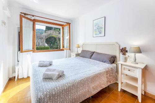 a white bedroom with a bed and a window at Bouganvillea in Port de Soller