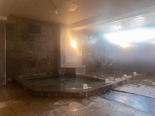 a bath tub in a room with a pool of water at Tabist Hotel Chouseikaku in Yatsushiro