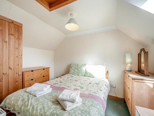 a bedroom with a bed with two towels on it at Stonefield Farm Cottage in Benmore