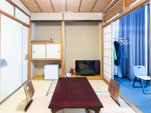 a living room with a table and a tv at Tabist Hotel Chouseikaku in Yatsushiro