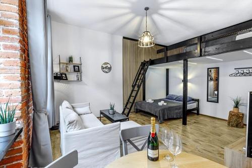 a living room with a bed and a table with a bottle of wine at Rzeźnicza 24 in Wrocław