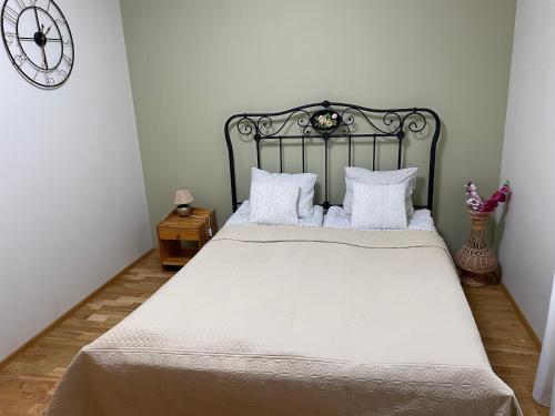 1 dormitorio con 1 cama con sábanas blancas y reloj en City Center Tartu mnt - FREE Parking, en Tallin