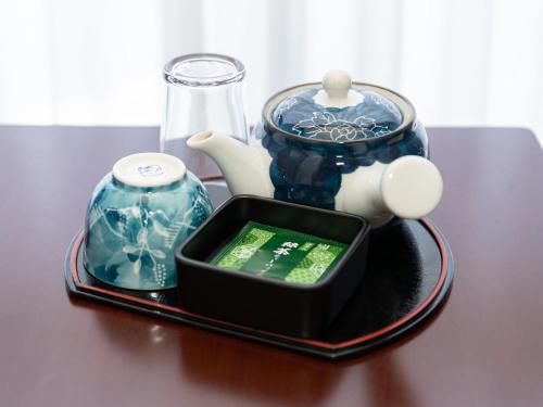 a table with a tray with a tea set and a tea pot at Tabist Hotel Chouseikaku in Yatsushiro
