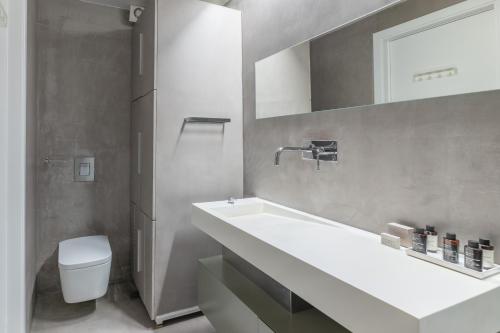 a bathroom with a sink and a toilet and a mirror at Elegant 2BR Apartment in Kolonaki by UPSTREET in Athens