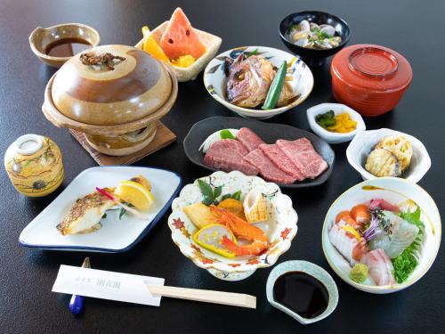 a table with plates of food and bowls of food at Tabist Hotel Chouseikaku in Yatsushiro