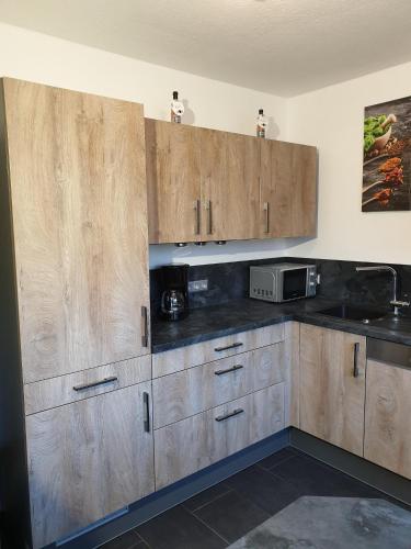 a kitchen with wooden cabinets and a microwave at Ferienwohnung Maya in Losheim