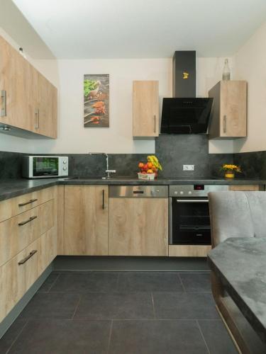 a kitchen with wooden cabinets and a stove top oven at Ferienwohnung Maya in Losheim
