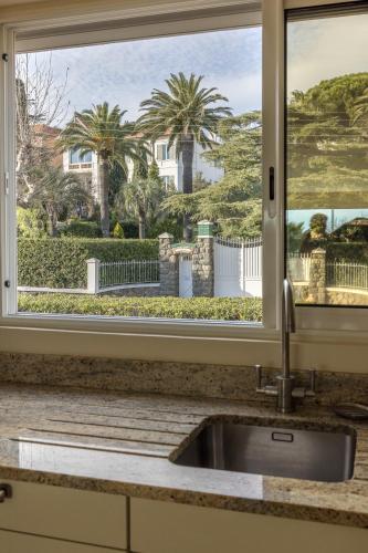 d'un évier de cuisine avec une fenêtre offrant une vue sur une maison. dans l'établissement Villa Montfleuri, vieille ville à pieds, vue mer, piscine, 8 pers, à Sainte-Maxime